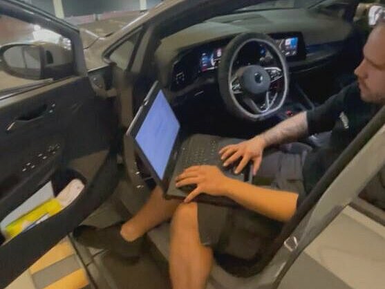 Im Auto am Laptop sitzender Kfz-Mechatroniker kalibriert die Frontkamera im Auto nach dem Scheibentausch neu.