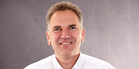 Portrait des Geschäftsführers Hans Thierolf vor grauem Hintergrund.
