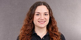 Portrait der Servicemitarbeiterin Meike Wetterauer vor grauem Hintergrund.
