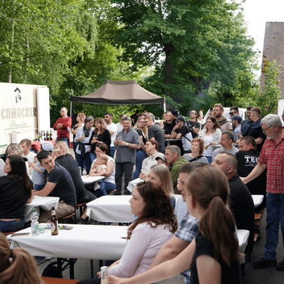 Bild von Mitarbeitenden und Familien auf Bierzeltgarnituren und stehend.