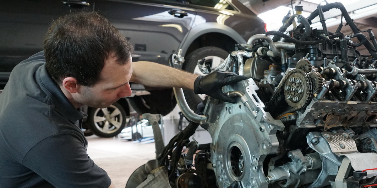 Kfz-Mechatroniker arbeitet an ausgebautem Automotor in der Autohaus-Thierolf-Werkstatt.